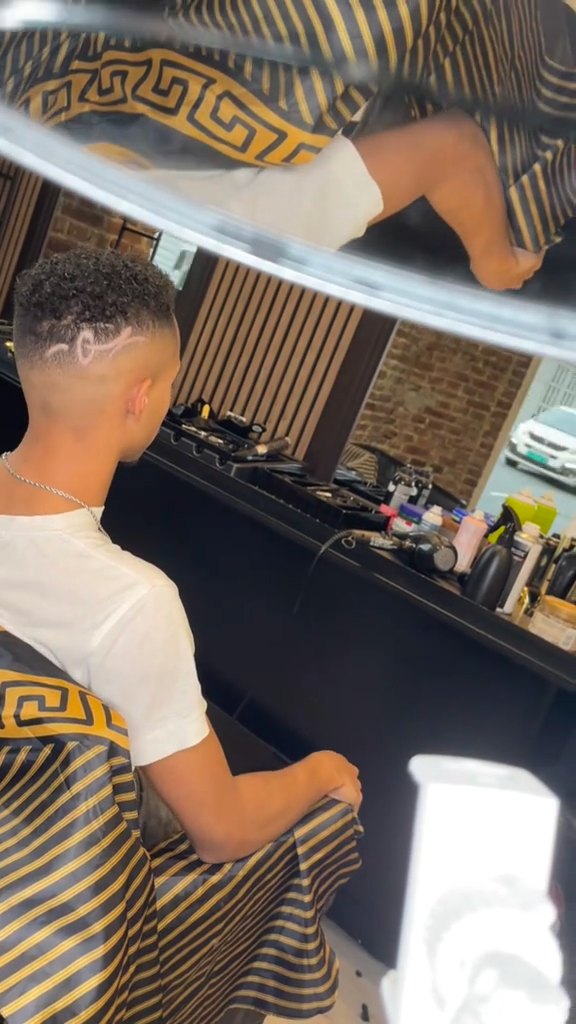 Skin fade med mønster, kunde i gullmønstret kappe